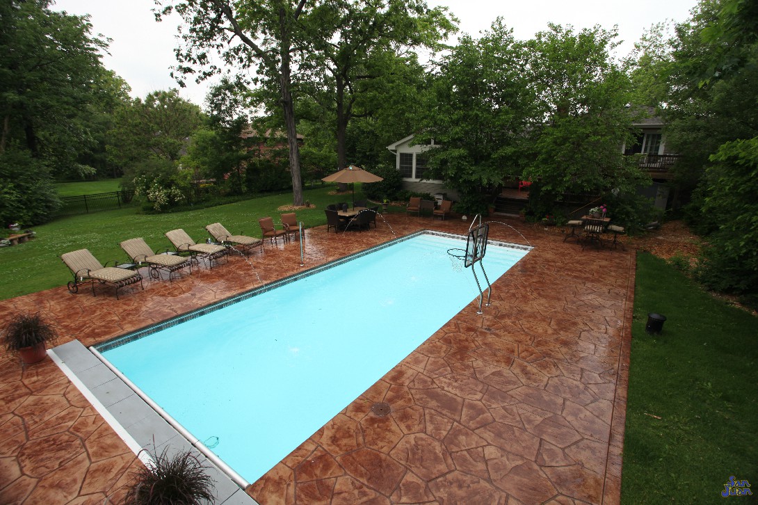 Oceanside fiberglass pool with deck jets stamped and stained concrete deck jets and basketball set