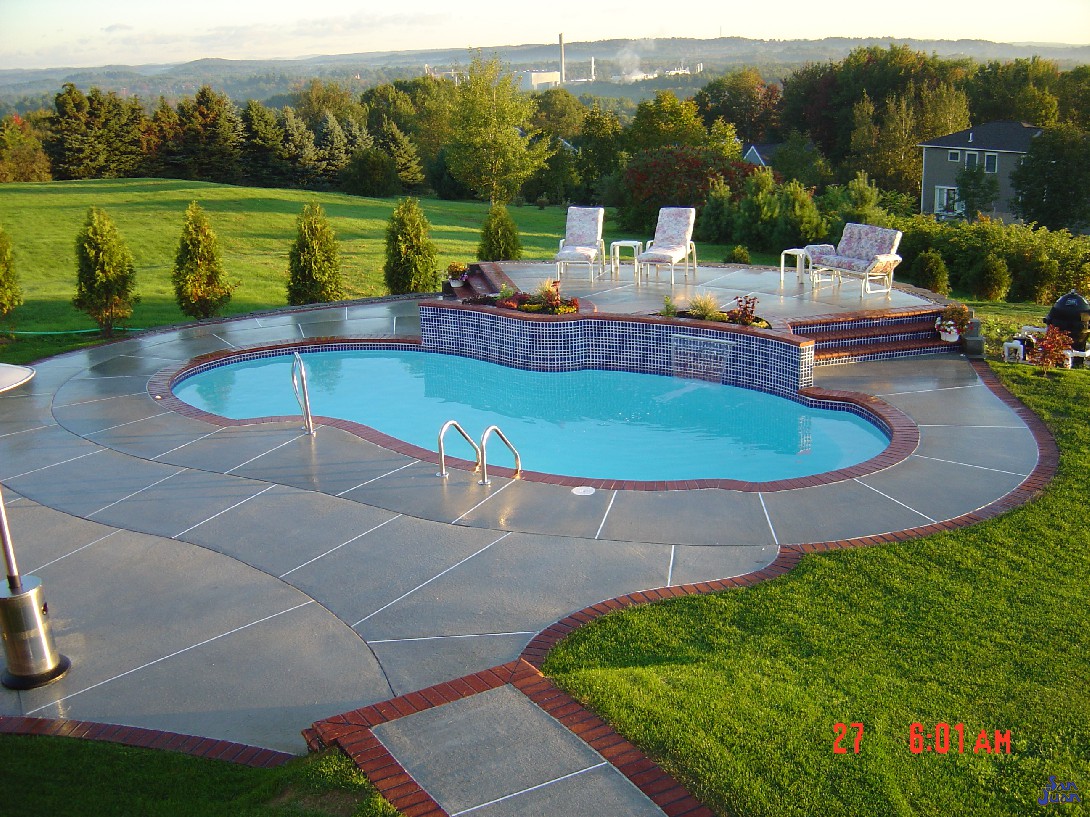 atlantic pool shape with concerte decking and raised patio next to beautiful grass field