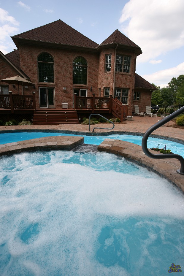 atlantic pool shape with raised spa behind large house