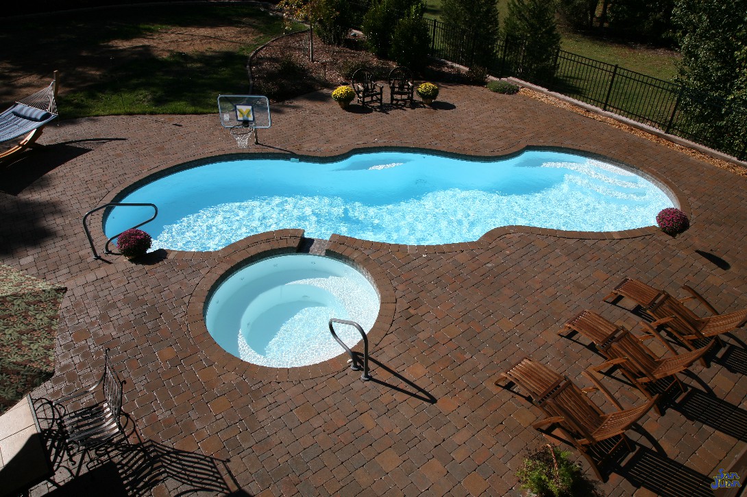 mirage pool shape with brick pavers handrails basketball goal and raised spa