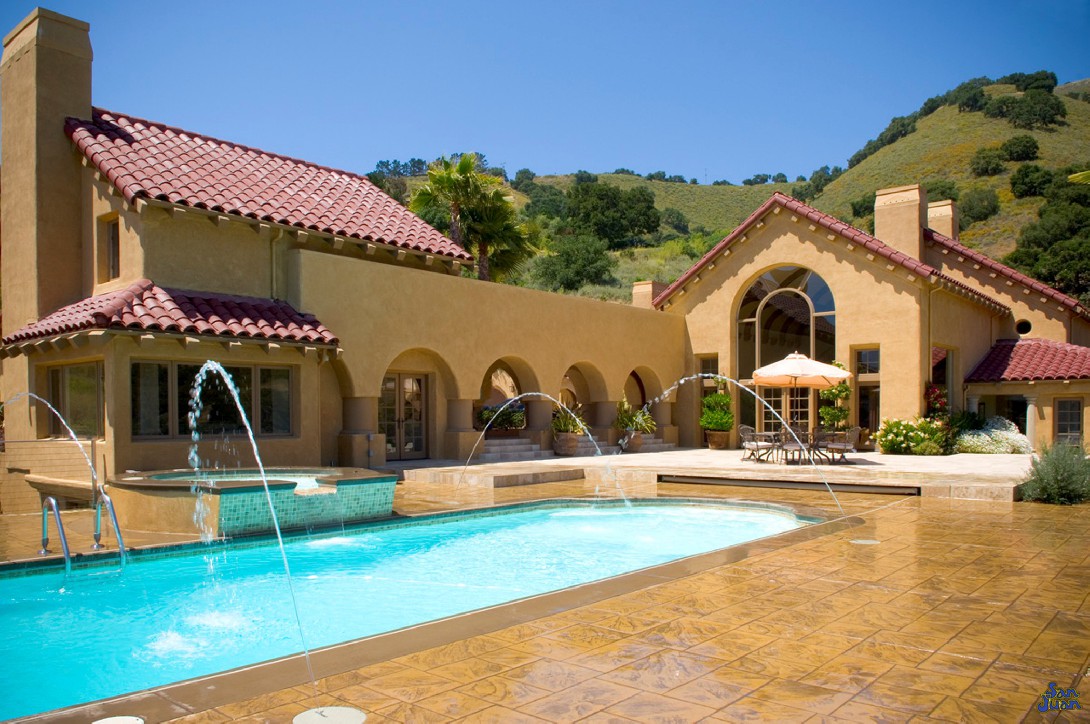 pacific fiberglass pool with raised waterfall deck jets and stamped stained concrete