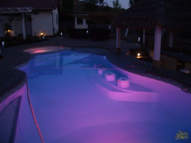 pleasure island fiberglass pool shape at night with purple led lighting