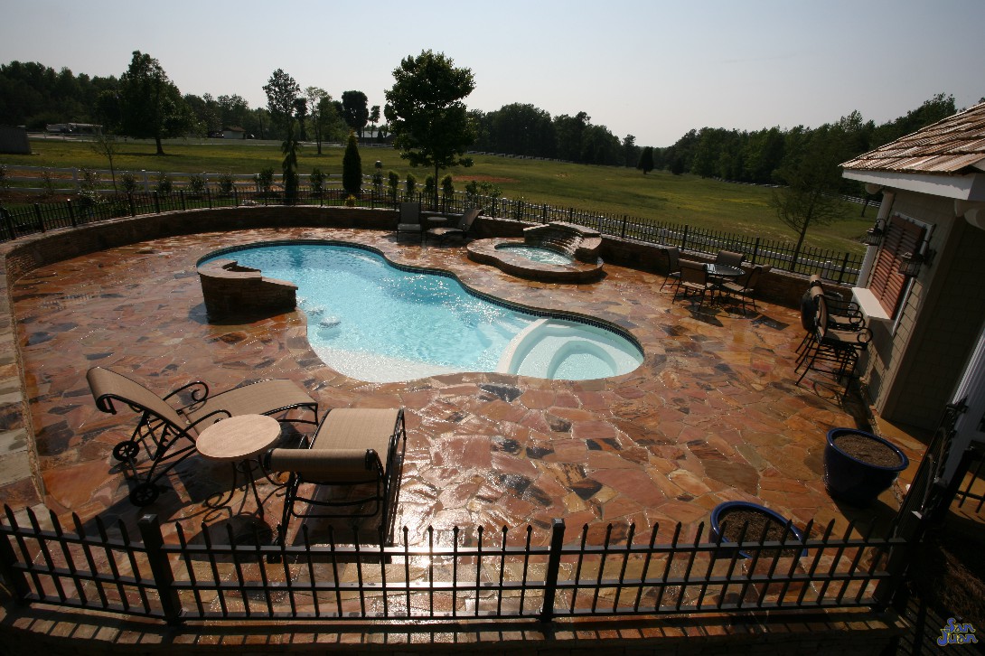 pleasure island fiberglass pool shape with natural travertine decking and outdoor kitchen