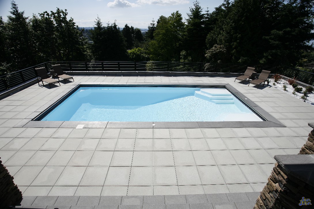 This image does a great job of illustrating the variability of this swimming pool. You can see just how quickly the shallow end gives way to the deep end basin. It also elegantly displays the beauty of this swimming pool when paired with a modern design - such as this square pattern travertine decking. 