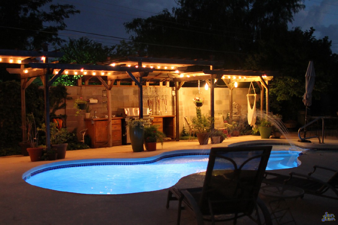 Here is another view of this gorgeous swimming pool at night with all illumination turned on. You can see how adding a little landscaping can really boost the beauty of your overall backyard experience. We can help you with these design approaches if you're looking for ways to achieve the same look.