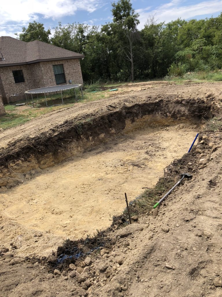 You've guessed it! We need to dig a hole to set this fiberglass pool shell. Unfortunately, we encountered heavy rains the day of our delivery so we were placed a little off schedule due to muddy conditions. However, you can see our excavated hole with a base layer of sand where the belly of our fiberglass swimming pool will lay. 